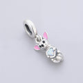 Close-up of a Chihuahua dog charm with a pink enamel ear and opal heart